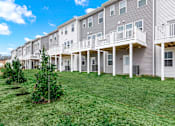 Thumbnail 57 of 57 - A row of townhouses with white balconies and grey siding.