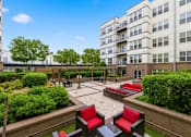 Thumbnail 42 of 57 - A courtyard with red and black chairs and a brick wall.