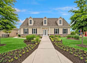 Thumbnail 8 of 14 - A house with a grey roof and a white door is surrounded by a garden with yellow flowers.