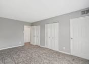 Thumbnail 2 of 14 - A room with grey walls and carpeted floor with three white doors.