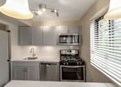 Thumbnail 3 of 12 - A modern kitchen with stainless steel appliances and a white countertop.