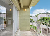 Thumbnail 1 of 14 - A balcony with a glass door leading to a patio.
