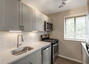 Thumbnail 4 of 12 - A kitchen with a stainless steel sink and a microwave above it.