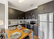Thumbnail 32 of 57 - A modern kitchen with a wooden table and grey cabinets.