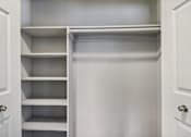 Thumbnail 14 of 14 - A white closet with shelves and doors.