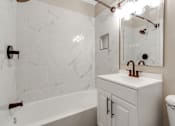 Thumbnail 5 of 12 - A white bathroom with a marble wall and a white sink.