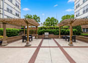 Thumbnail 44 of 57 - A courtyard with a fountain and benches under wooden pergolas.