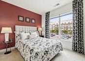 Thumbnail 25 of 57 - A bedroom with a large bed and a window overlooking a parking lot.