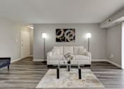 Thumbnail 2 of 11 - A modern living room with a white couch and a large abstract painting on the wall.