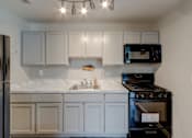 Thumbnail 5 of 11 - A kitchen with white cabinets and a black stove.