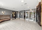 Thumbnail 50 of 57 - A spacious lobby with a bench and glass doors.