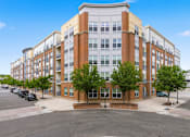 Thumbnail 46 of 57 - A large multi-story building with a parking lot in front.
