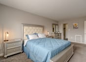 Thumbnail 7 of 11 - A bedroom with a blue bedspread and a white headboard.