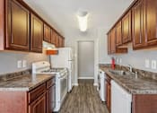 Thumbnail 11 of 14 - A kitchen with white appliances and brown cabinets.