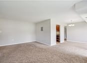 Thumbnail 12 of 14 - A large, empty room with a carpeted floor and white walls.