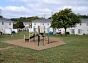 Thumbnail 30 of 33 - A playground with a swing set and a slide in the middle of a grassy area.
