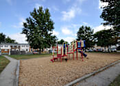 Thumbnail 11 of 33 - A playground with a red swing set and a blue slide.