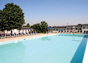 Thumbnail 8 of 33 - A large outdoor swimming pool with blue water and lounge chairs.