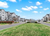 Thumbnail 28 of 57 - A row of apartment buildings with a grassy area in the foreground.