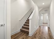 Thumbnail 46 of 57 - A hallway with a staircase and white walls.