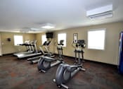 Thumbnail 33 of 33 - A gym with treadmills and elliptical machines.