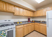 Thumbnail 3 of 18 - A kitchen with wooden cabinets and a white refrigerator.