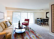 Thumbnail 4 of 18 - A living room with a couch, a chair, a coffee table, and a dining table.