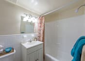 Thumbnail 9 of 18 - A white sink in a bathroom with a blue towel hanging on the tub.