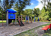 Thumbnail 14 of 18 - A playground with a blue shelter, red slide, and a red bench.