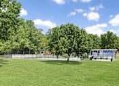 Thumbnail 16 of 18 - A green field with trees and a building in the background.