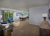 Thumbnail 9 of 11 - A living room with a grey couch, a blue chair, a wooden table, and a television.