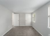 Thumbnail 14 of 29 - an empty bedroom with two doors and a carpeted floor
