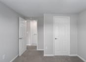 Thumbnail 24 of 29 - an empty bedroom with two doors and a carpeted floor