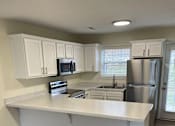 Thumbnail 23 of 23 - A kitchen with white cabinets and a white island.