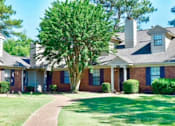 Thumbnail 4 of 15 - A house with a brick facade and a large tree in front.