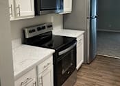 Thumbnail 4 of 42 - A kitchen with white cabinets and a black microwave.
