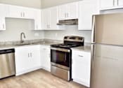 Thumbnail 11 of 15 - A kitchen with white cabinets and a stainless steel refrigerator.