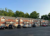 Thumbnail 7 of 23 - a parking lot filled with cars in front of a brick apartment building