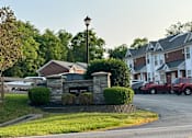Thumbnail 1 of 23 - the front yard of an apartment building with a parking lot and a street sign
