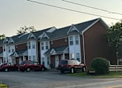 Thumbnail 8 of 23 - a brick apartment building with three cars parked in front of it