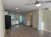 Thumbnail 10 of 23 - an empty living room and kitchen with wood floors and a black refrigerator