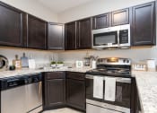 Thumbnail 15 of 22 - a kitchen with black cabinets and a stove and a microwave