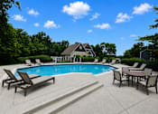 Thumbnail 3 of 26 - A pool surrounded by chairs and a house in the background.