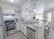 Thumbnail 16 of 26 - A modern kitchen with a stainless steel refrigerator, a stove, and a marble countertop.