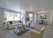 Thumbnail 25 of 26 - A living room with a white sofa, a white armchair, and a coffee table.