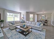Thumbnail 6 of 26 - A living room with a large sectional sofa and a coffee table.