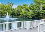 Thumbnail 9 of 26 - A fountain in the middle of a lake surrounded by trees.