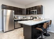 Thumbnail 7 of 17 - A kitchen with a marble countertop and a stainless steel refrigerator.