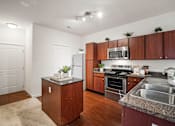 Thumbnail 2 of 38 - A kitchen with wooden cabinets and a granite countertop. at Aventura at Richmond, St. Peters, 63376