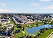 Thumbnail 38 of 41 - A suburban neighborhood with a pond and a road running through it.